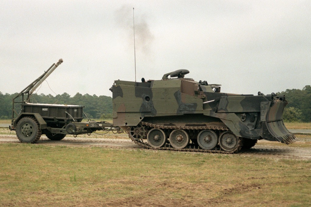 An M-9 Armored Combat Earth Mover (ACE) is pulling a Mine Clearing Line Charge (MICLIC) system.